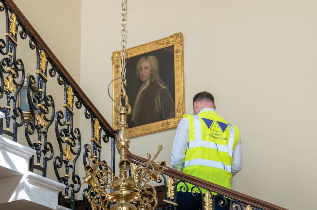 Male construction professional wearing a high-visibility vest inside a modern, upscale office environment, representing Everist’s expertise in commercial projects for prestigious London buildings.